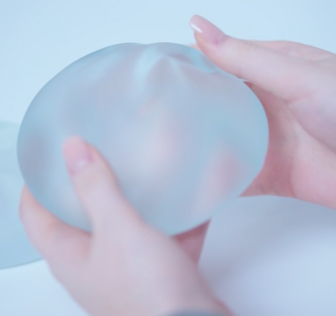 Nahaufnahme Frauenhände halten Brustimplantat