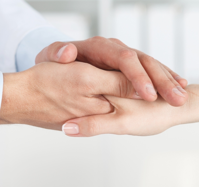 Nahaufnahme Patientenhand wird von Ärztehand gehalten, symbolisiert Leitbild