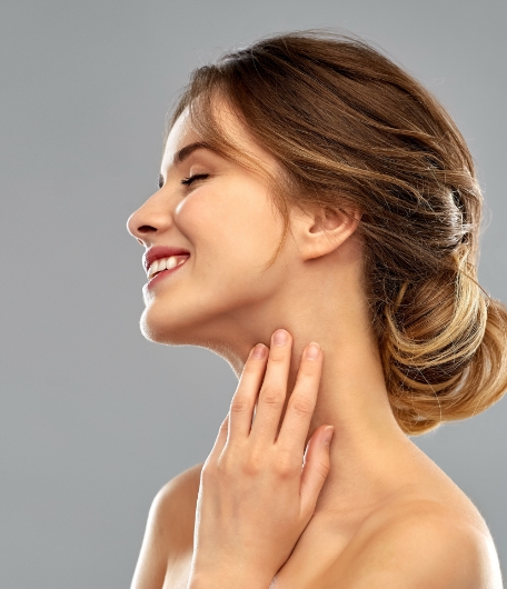 Lächelnde Frau, die ihren Hals berührt, steht für Halsstraffung